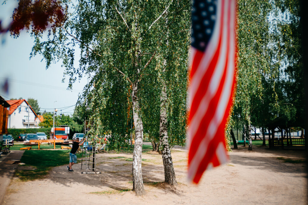 Ania i Samuel.Zdjęcie przedstawia flagę amerykańską która wisi na budynku Camp Ostróda. Jest ciepły wrześniowy poranek.